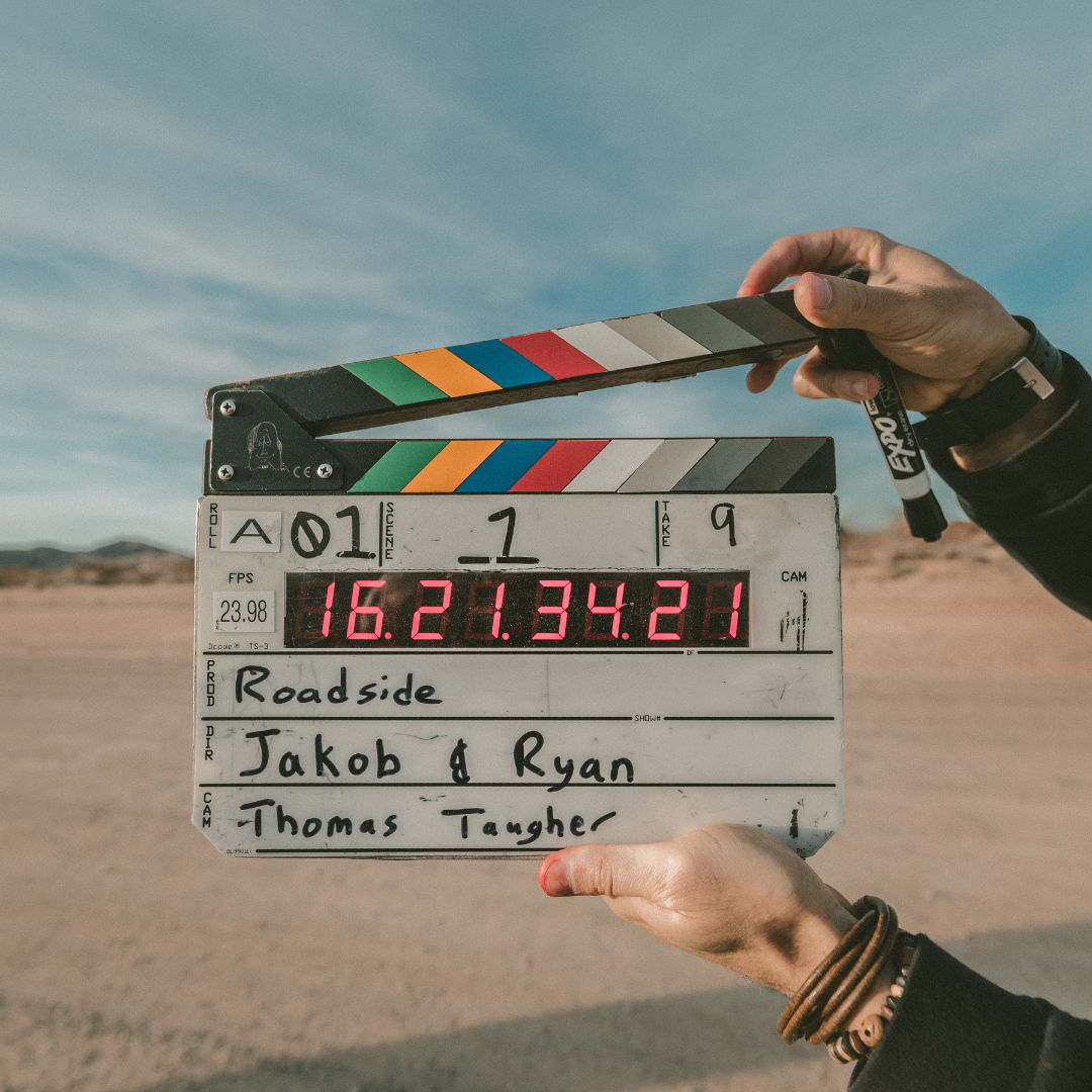 white woman holding a clapperboard against a sandy background
