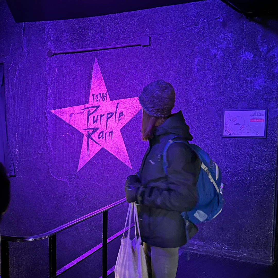 Person looking at a painted star on a purple wall with the words Purple Rain