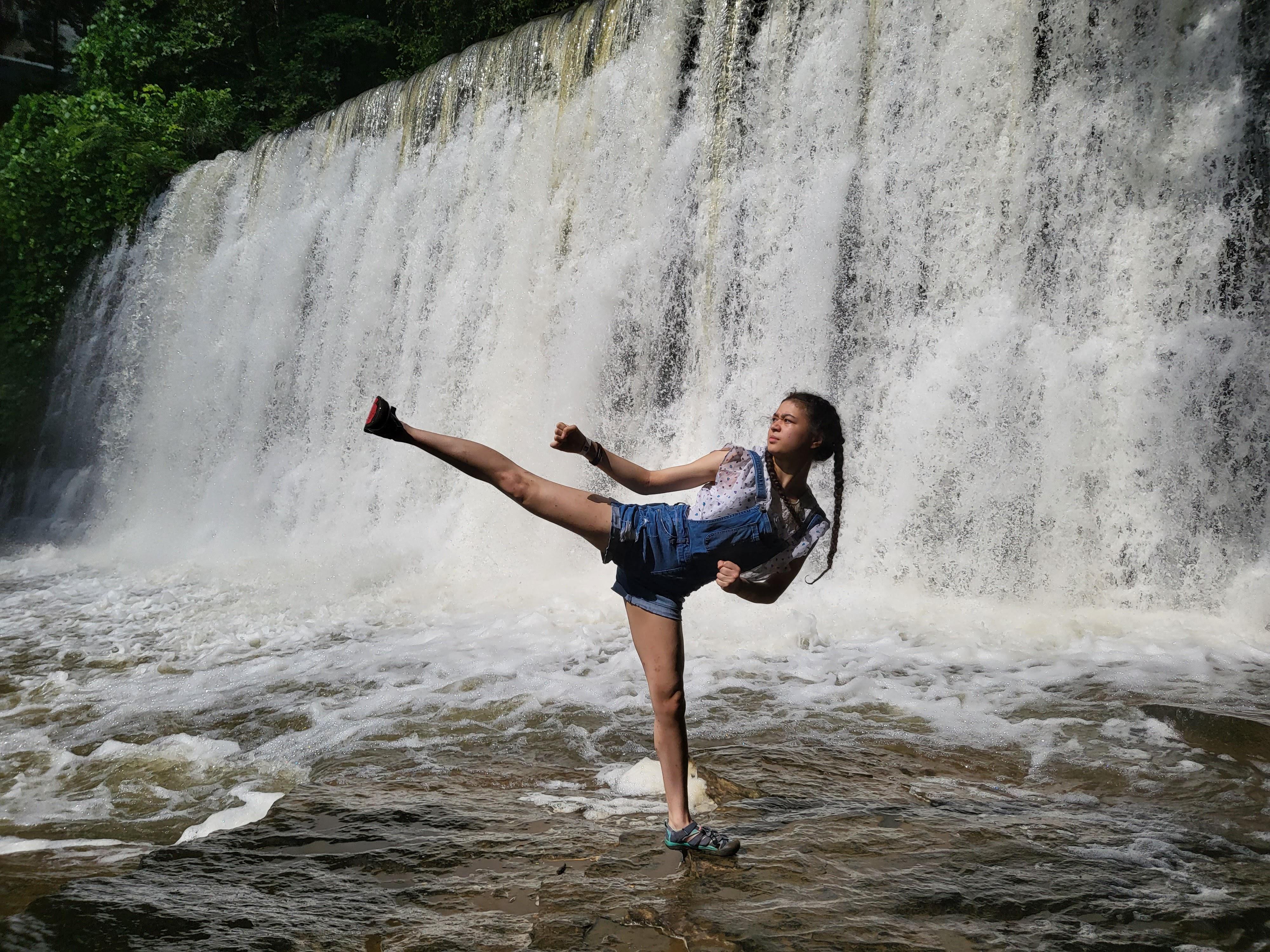 UHP student Natalia Hong doing a side kick in front of a waterfall