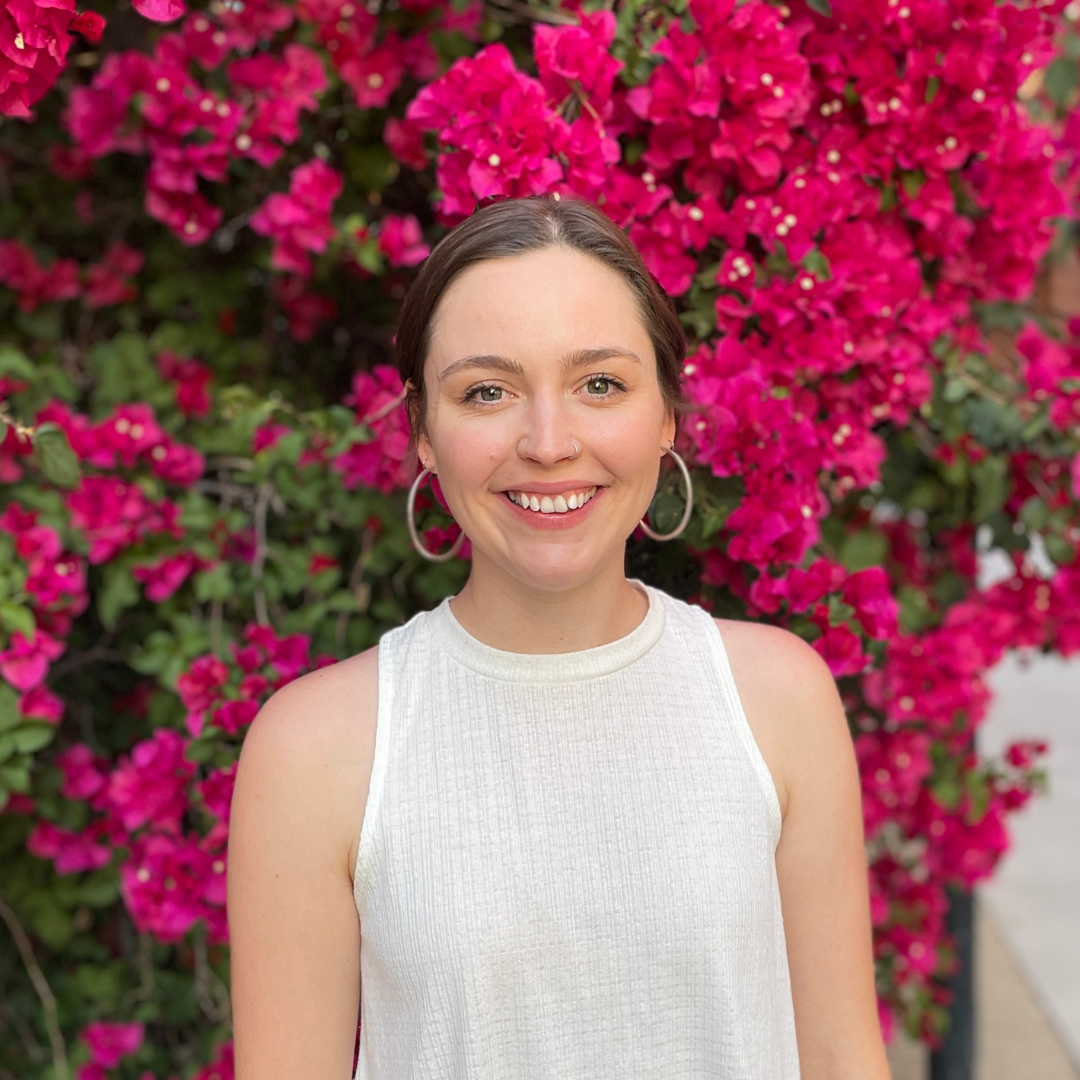 Headshot of Talia Anderson in front of bright pink flowers